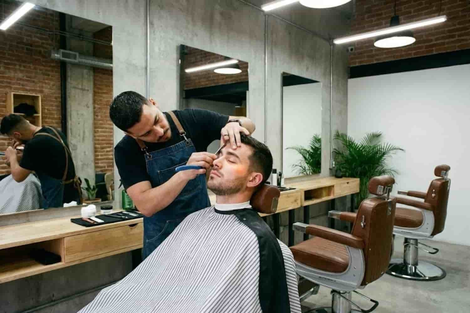 Barbero profesional realizando perfilado de cejas y limpieza facial a un hombre en Tlalnepantla.